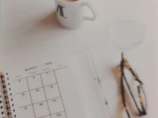 Eine Brille und ein Kalender liegen auf einer weißen Tischplatte, daneben eine Tasse Kaffee. Im Vordergrund das Wort Planning mit einem Bleistift und im Hintergrund das Wort Change.
