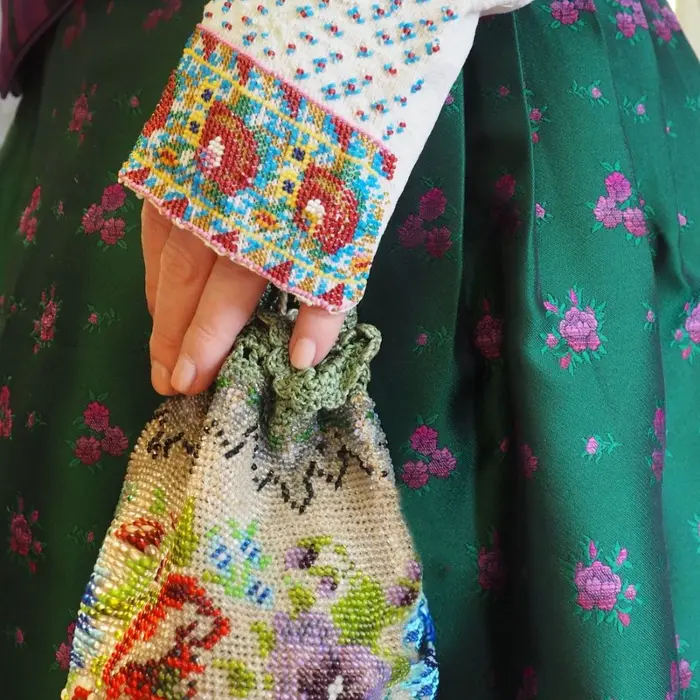 Hand mit gestickter Stulpe und gesticktem Beutel 