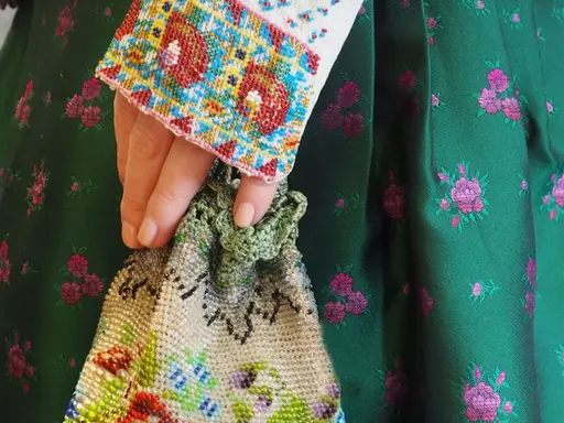 Hand mit gestickter Stulpe und gesticktem Beutel 