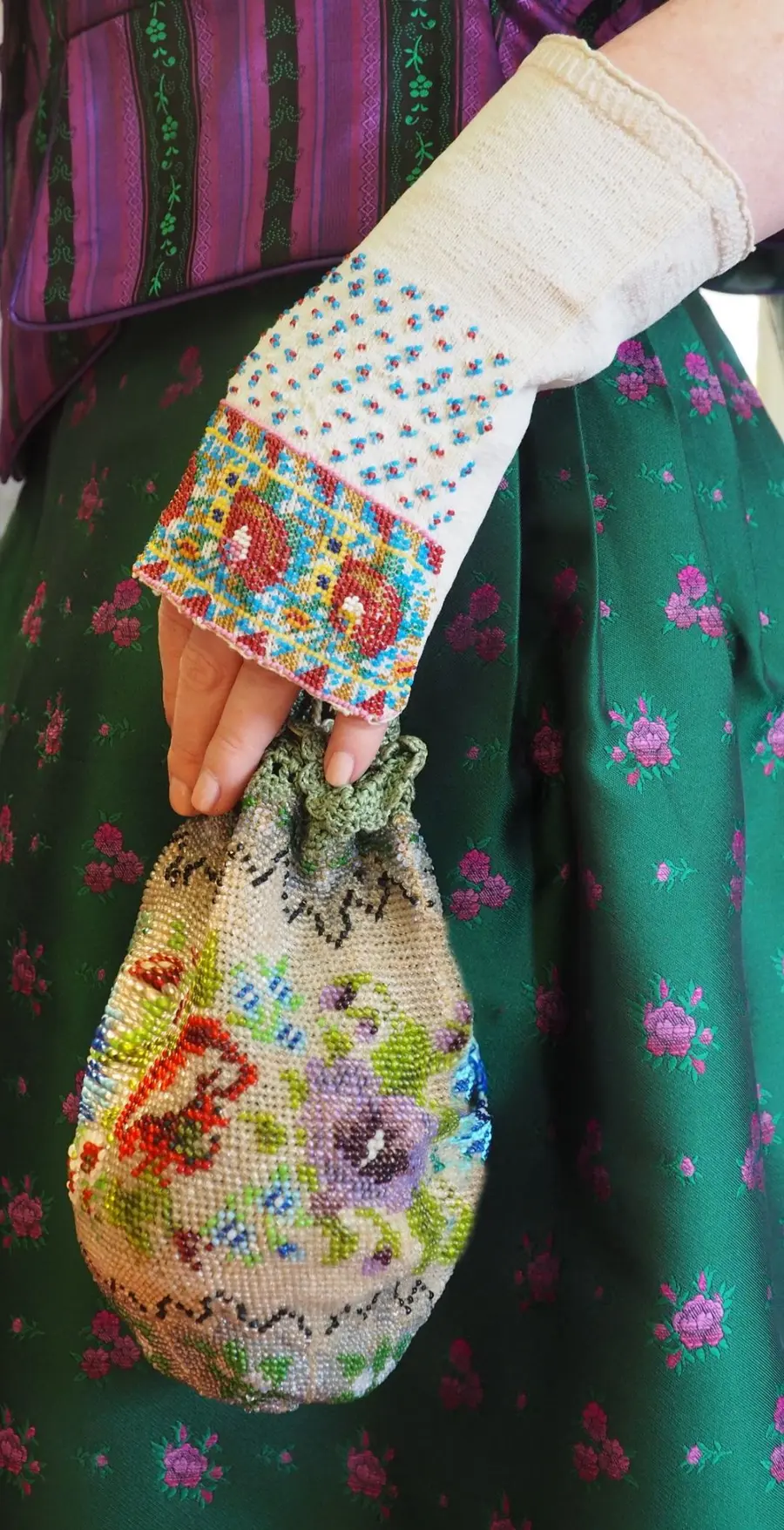 Hand mit gestickter Stulpe und gesticktem Beutel