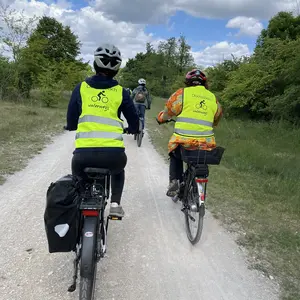 Blick von hinten auf eine Gruppe Radfahrer auf einem Feldweg 