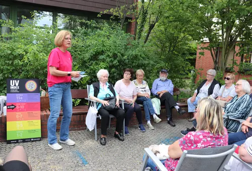 Teilnehmer eines Quiz zum Thema Hitzeschutz, links eine Infotafel zum UV-Index 