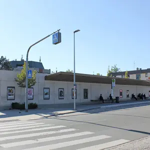 Die gesamte Platzwand mit den neuen Medien und Bushaltestelle von der anderen Straßenseite aus gesehen