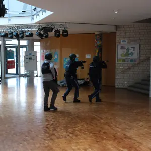 drei Polizeipersonen in Kampmontur in einem Schulgebäude