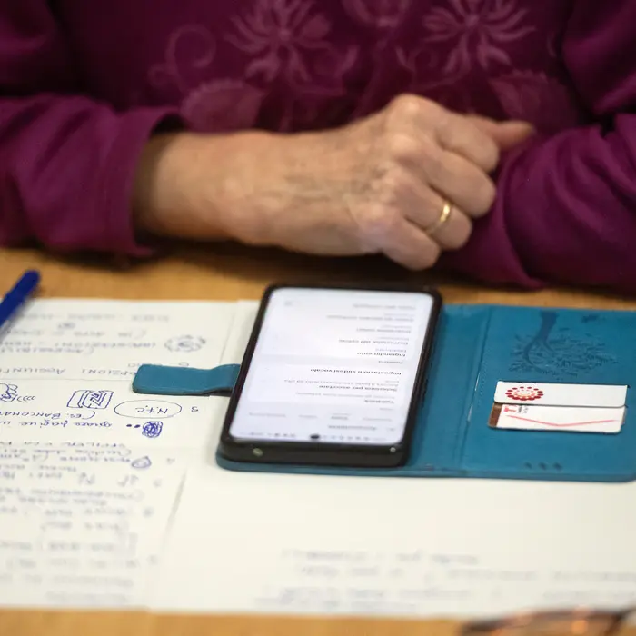 Close-up auf Notizzettel und Handy und die Hand einer älteren Person 