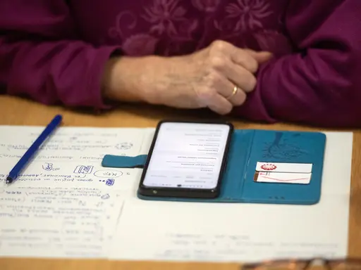 Close-up auf Notizzettel und Handy und die Hand einer älteren Person