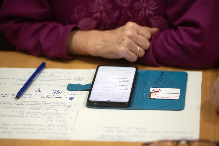 Close-up auf Notizzettel und Handy und die Hand einer älteren Person 