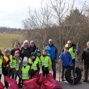 Acht begeisterte Kinder mit sechs Erwachsenen und ihren Müllsäcken sowie einem Autoreifen