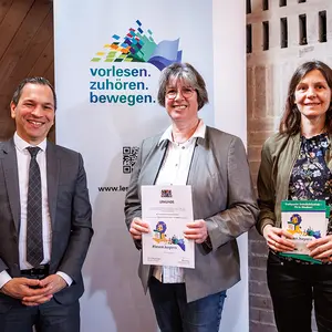 Ein Mann hat zwei Frauen eine Urkunde überreicht