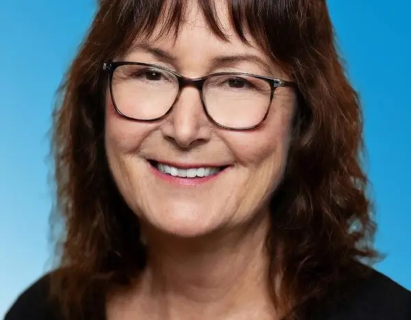 Frau mit schwarzer Bluse, langen dunklen Haaren und Brille 