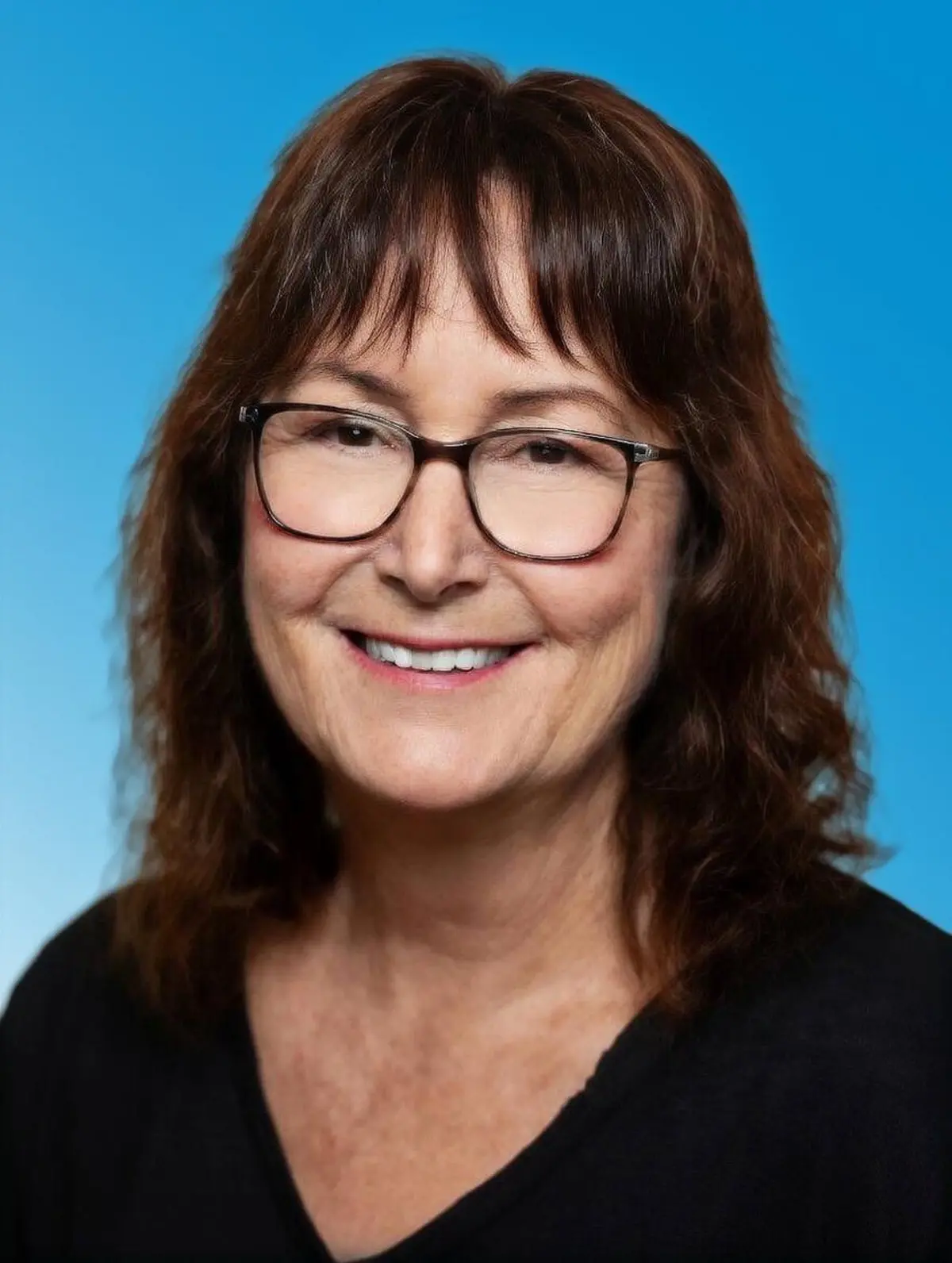 Frau mit schwarzer Bluse, langen dunklen Haaren und Brille