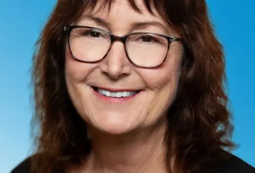 Frau mit schwarzer Bluse, langen dunklen Haaren und Brille 