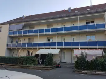 Mehrfamilienhaus mit Etagenwohnungen und Balkonen mit blauem Sichtschutz