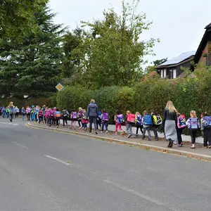 Kinder in Zweierreihen mit ihren Betreuerinnen auf dem Gehweg.