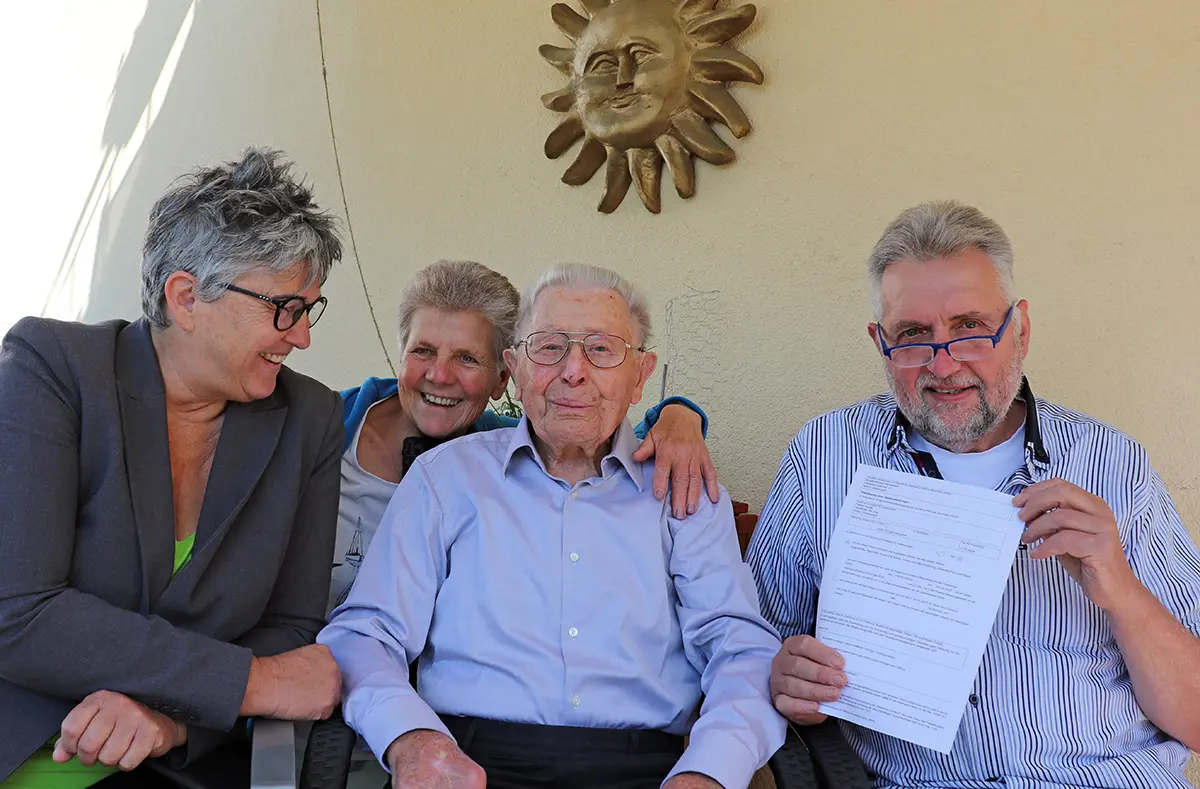 Zwei Männer und zwei FRauen sitzen auf einem Balkon und schauen in die Kamera.
