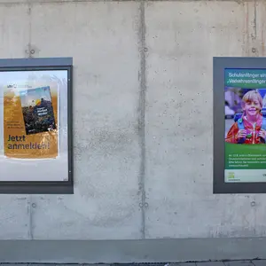 Nahaufnahme eines Aushangkastens und eines digitalen Bildschirms