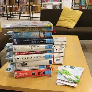 Stapel mit Büchern, aus denen die neuen Buchtipp-Karten herausragen, daneben einige leere Karten mit Kugelschreibern
