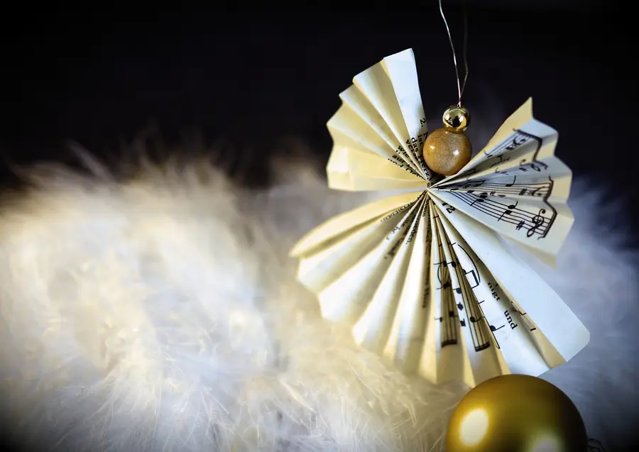 ein Engel aus einem Notenblatt gefaltet mit einer kleinen Holzkugel als Kopf