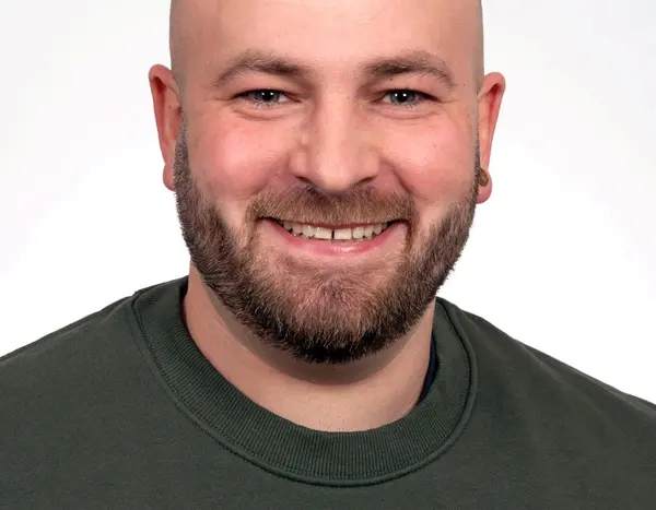 Mann mit Vollbart und Glatze im schwarzen Pulli 