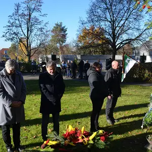 Vier Menschen in gedenkender Haltung bei der Kranzniederlegung