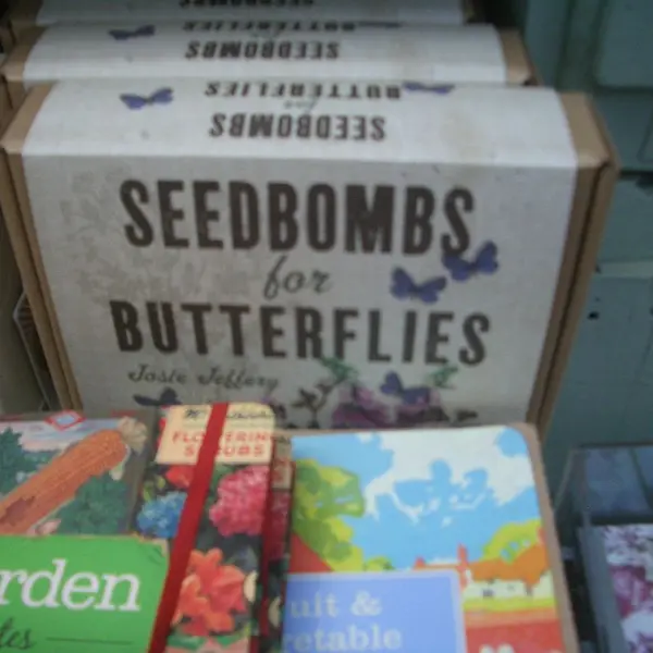 Ein Kasten mit der Aufschrift "seedbombs for butterflies". Davor angeschnittene Gartenbücher. 