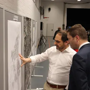 Zwei Männer im Gespräch vor einer Landkarte