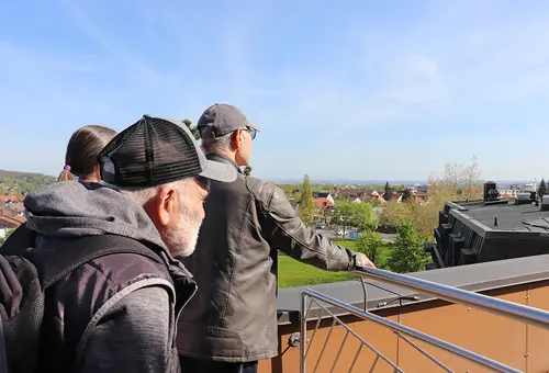 Drei Männer blicken von der Dachterrasse in die Ferne.