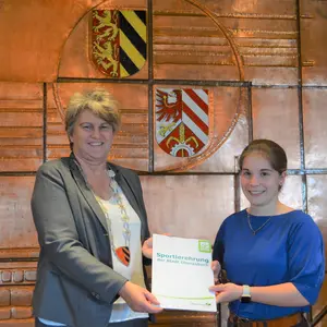 Eine Frau überreicht einer anderen eine Urkunde