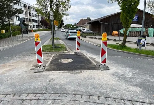 Ein Straße - ein Teil ist neu asphaltiert. Darum herum stehen drei Barken. 