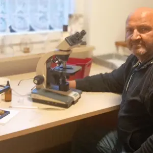 Mann sitzt for Mikroskop