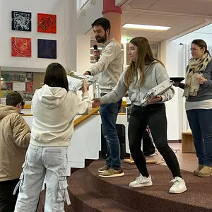 Eine Lehrerin übergibt einer Schülerin ihr Arbeitsgerät.