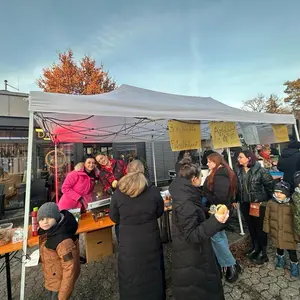 Verkaufsstand mit Frauen, die Bratwurstbrötchen verkaufen. Kunden die vor der Zeltausgabe stehen.