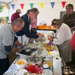 Zwei Männer und eine Frau in der Küche und pellen Kartoffeln.