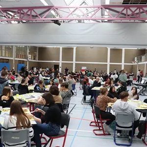 Blick in die mit vielen besetzten Tischen gefüllte Sporthalle.