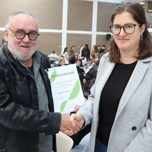 Ein alter Mann und eine junge Frau halten eine Ehrenurkunde 