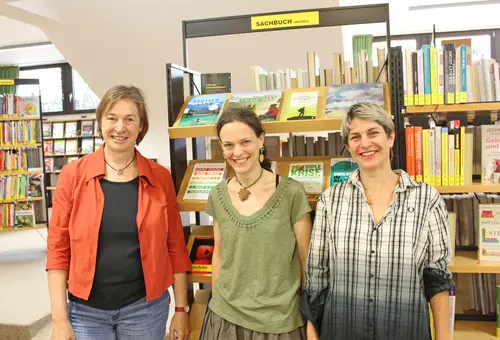 Drei Frauen vor einem Bücherregal