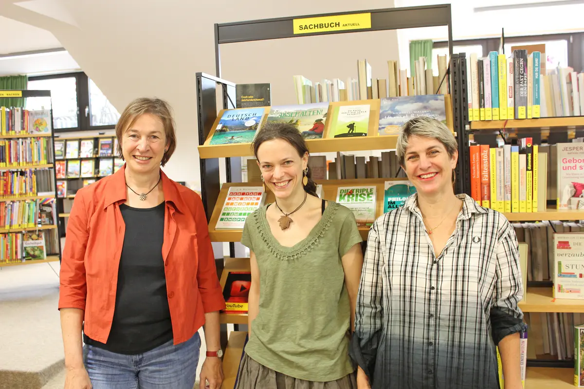Drei Frauen vor einem Bücherregal