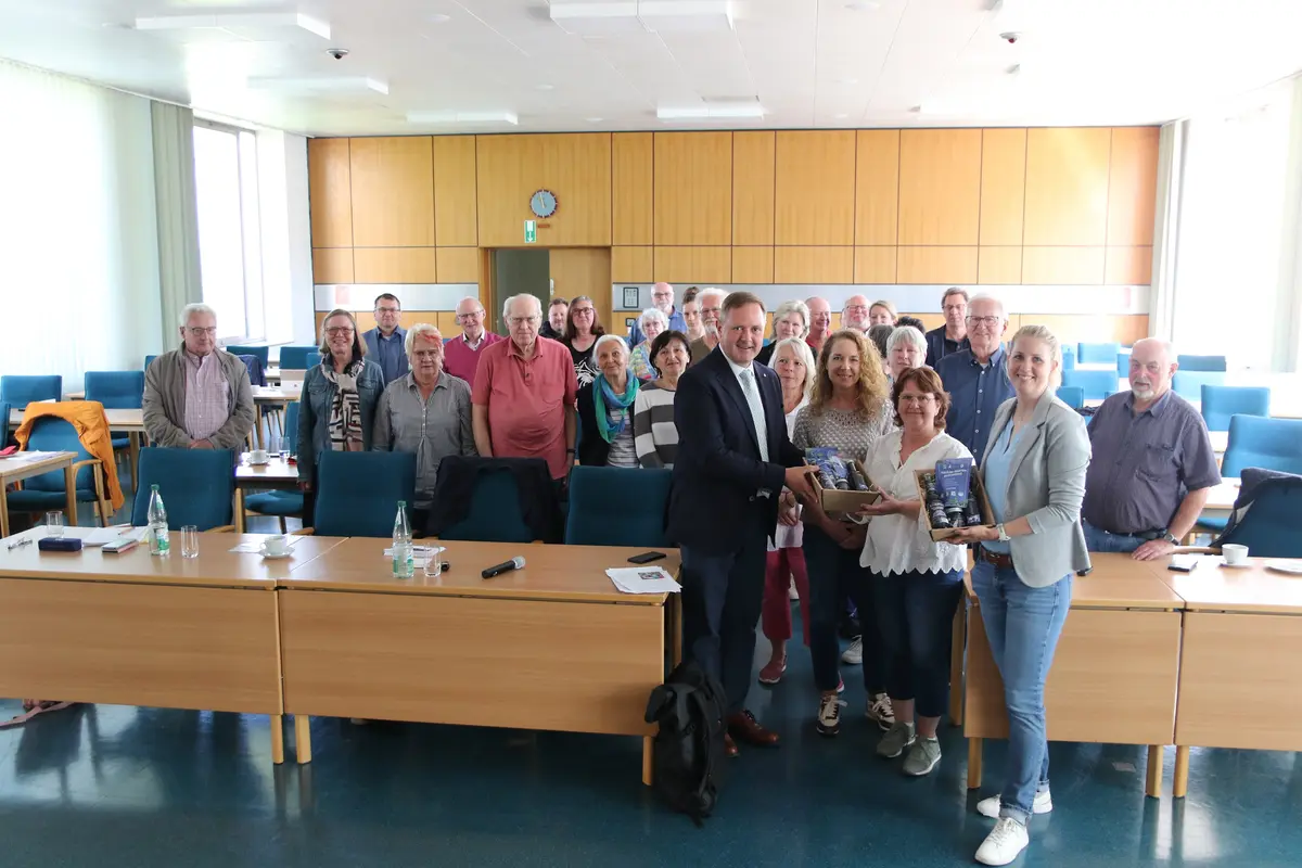 Eine Gruppe von alten Menschen. Es werden zwei Geschenkkörbe überreicht. 