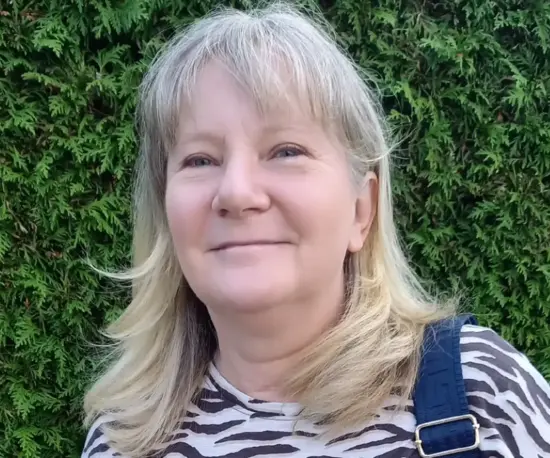 Frau im T-Shirt mit Tigerstreifen vor Hecke 