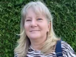 Frau im T-Shirt mit Tigerstreifen vor Hecke 