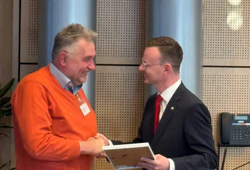 Ein Mann überreicht einen anderne Mann eine Urkunde