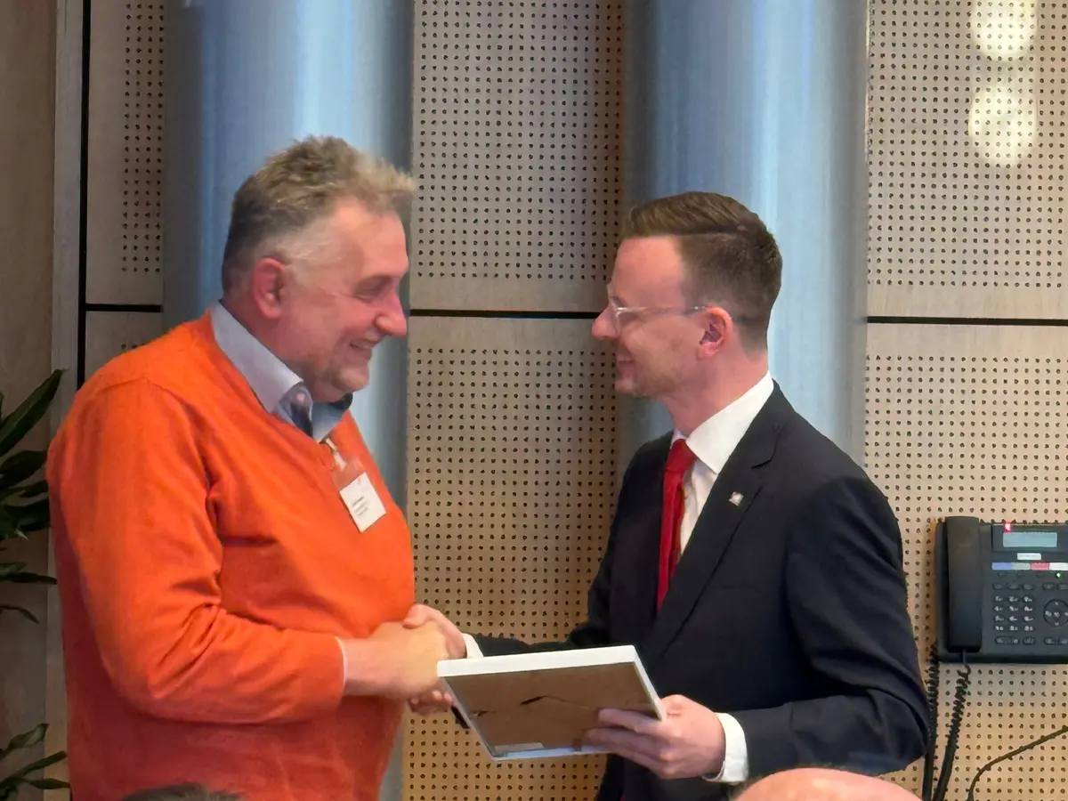 Ein Mann überreicht einen anderne Mann eine Urkunde