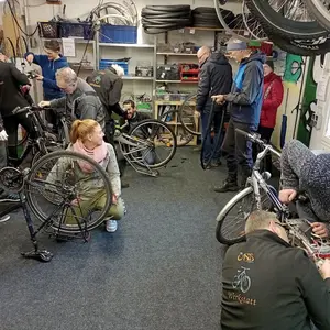 verschiedene Menschen arbeiten in der Werkstatt an Fahrrädern 