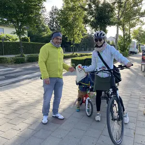 Frau und Kind mit Fahrrad, daneben ein Mann 