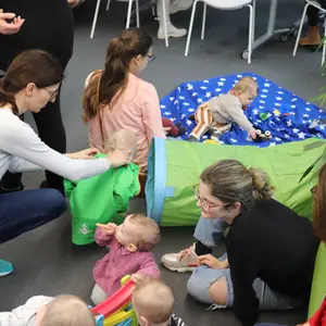 Mütter und Kinder in der Spieleecke mit Krabbeltunnel und Decke