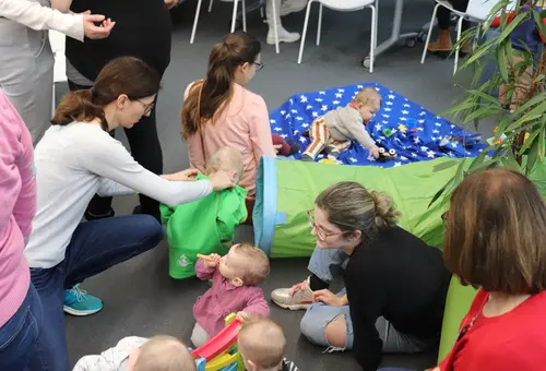 Mütter und Kinder in der Spieleecke mit Krabbeltunnel und Decke