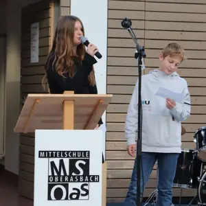 Mädchen mit langen Haaren und Junge mit Mikrofonen in der Hand. 