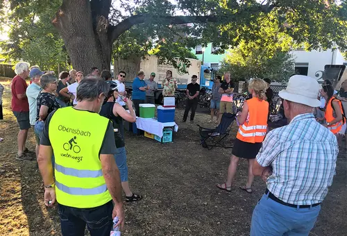 Menschen stehen im Kreis und besprechen sich unter einem großen Eichenbaum.