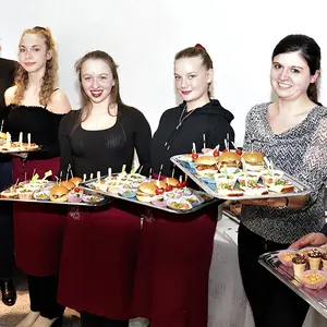 Sieben Personen präsentieren die Tabletts mit Häppchen und Finger Food.
