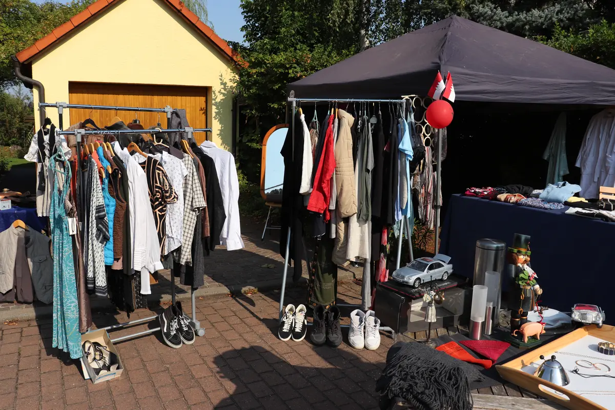 Kleiderstangen mit Second-Hand-Kleidung vor Garage 